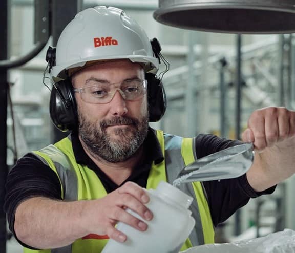 Male Biffa employee scooping pellet granules into container