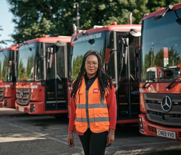 Female employee in front of waste vehicles