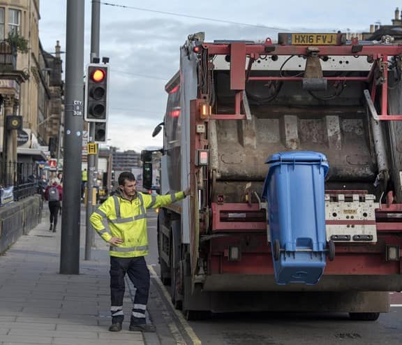 Man in high vis lifting bin into waste truck